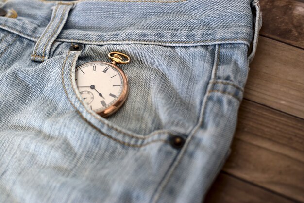 Réveil dans une poche de jeans sur une surface en bois - concept de gestion du temps