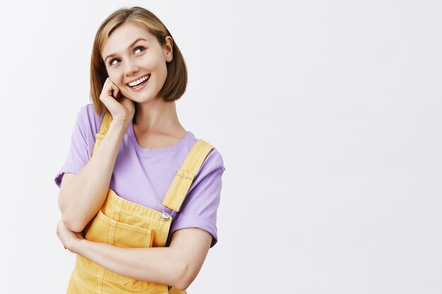 rêveuse jolie fille blonde, souriante et à la curieuse