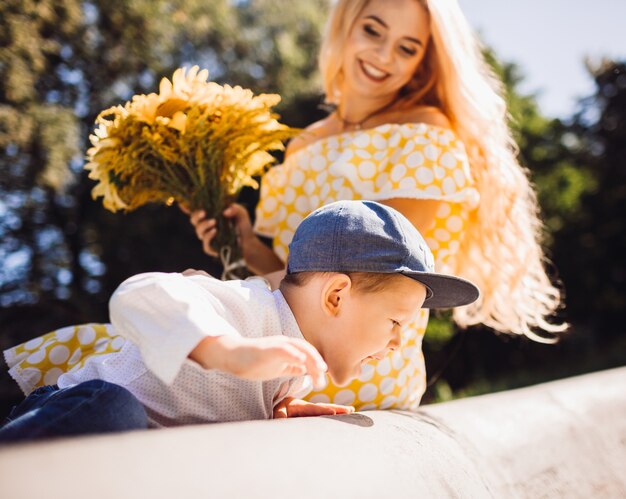 Rêveuse mère regarde son fils drôle assis dans le parc