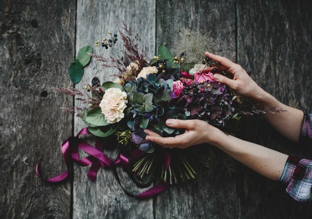 Riche bouquet de fleurs sombres et de roses blanches se trouve sur la table en bois