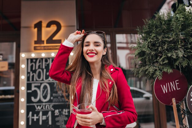 Rire adorable fille en veste rouge se promenant dans la rue