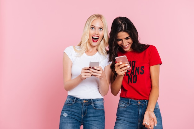 Rire des amis à l'aide de smartphones et souriant isolé