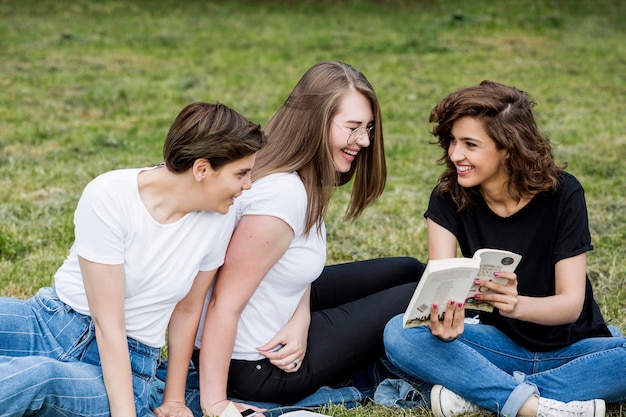 Rire des amis en regardant livre dans le parc