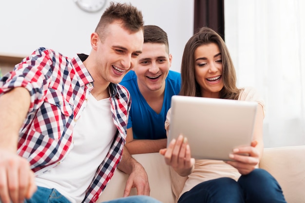 Rire d'amis avec tablette numérique à la maison