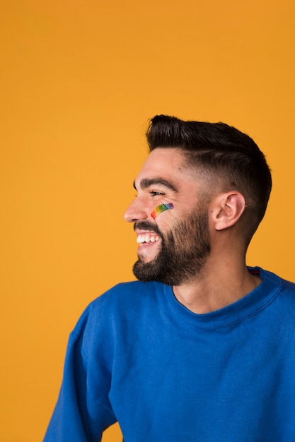 Rire bel homme avec arc-en-ciel LGBT sur le visage