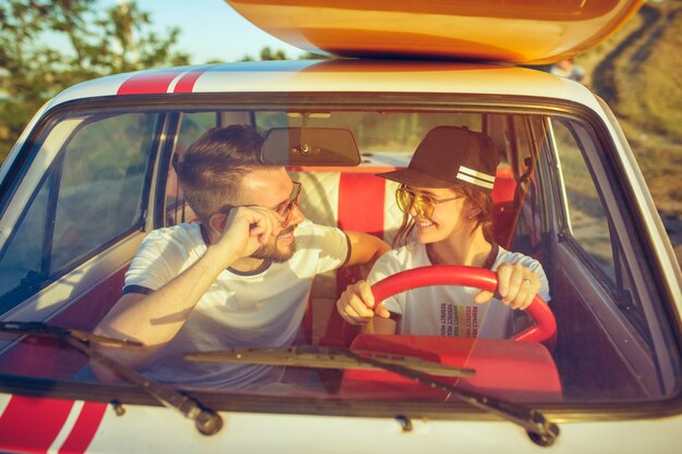 Rire couple romantique assis dans la voiture lors d'un voyage sur la route. Couple ayant pique-nique au jour d'été