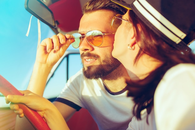 Rire couple romantique assis dans la voiture lors d'un voyage sur la route