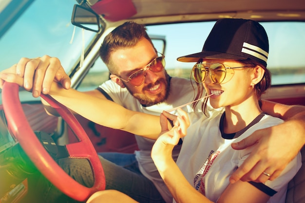 Rire couple romantique assis dans la voiture lors d'un voyage sur la route