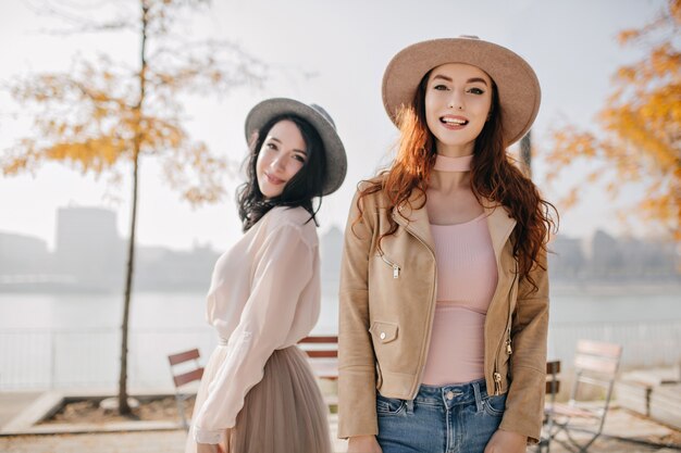 Rire femme rousse en chemise rose debout dans un café en plein air