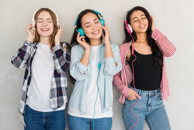 Rire des femmes debout et écouter de la musique dans des écouteurs colorés