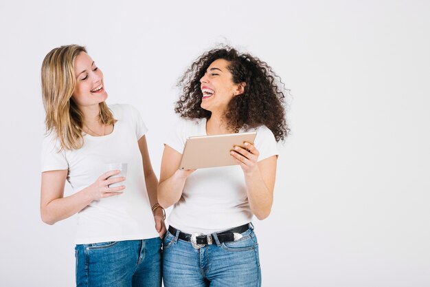 Rire des femmes en utilisant une tablette ensemble