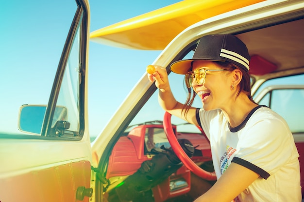 Rire fille assise dans la voiture lors d'un voyage sur la route près de la rivière