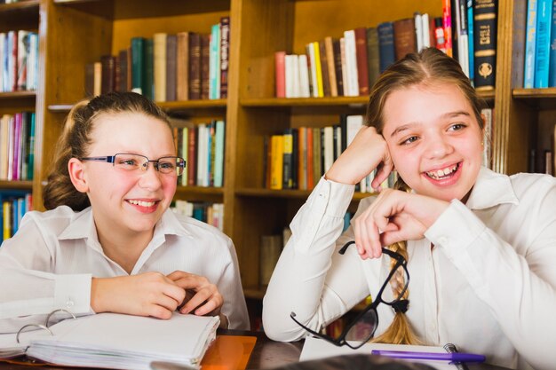 Rire des filles mignonnes assis avec des cahiers