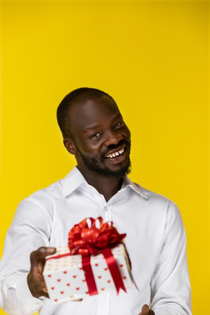 Rire jeune barbu afro-américain avec un cadeau