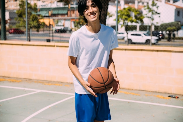 Rire, jeune homme, à, basket-ball, regarder caméra