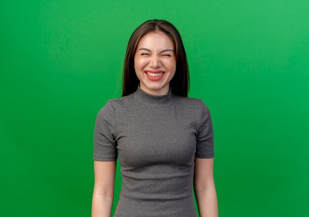 Rire jeune jolie femme aux yeux fermés isolé sur fond vert avec espace copie