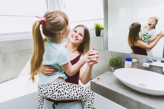 Rire mère et fille danser dans la salle de bain