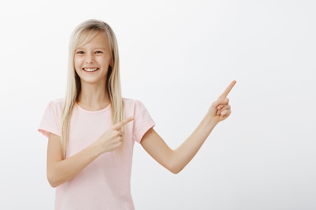 Rire et sourire adorable petite fille pointant le coin supérieur droit