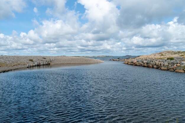 Rivière entourée de rochers sous la lumière du soleil et un ciel nuageux pendant la journée