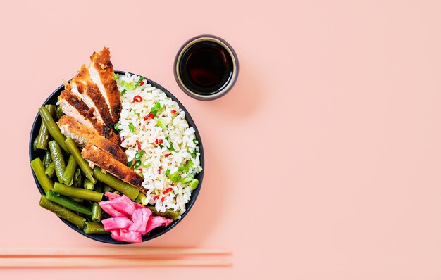 Riz aux épices, sauce soja et quartiers de dinde dans un bol noir avec haricots verts frits, piments forts et épices. Préparé au wok. Vue de dessus avec espace de copie. Idée de cuisine asiatique