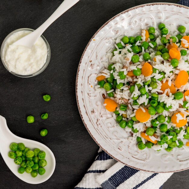 Riz aux haricots verts et carottes sur assiette près de sauce dans un bol