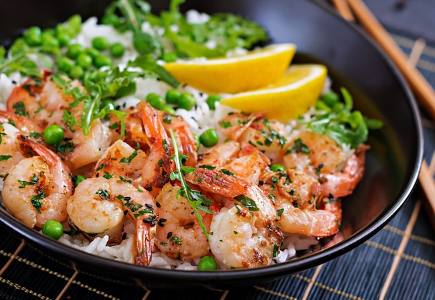 Riz aux petits pois verts, crevettes et roquette dans un bol noir. La nourriture saine. Bol de Bouddha.