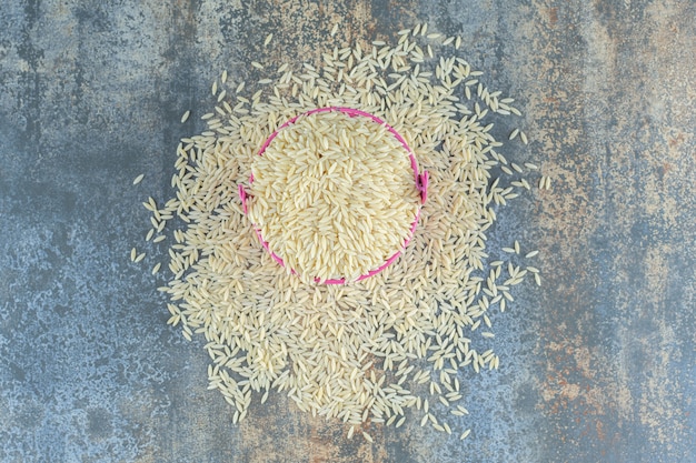 Photo gratuite riz basmati renversé d'un seau, sur la surface en marbre.