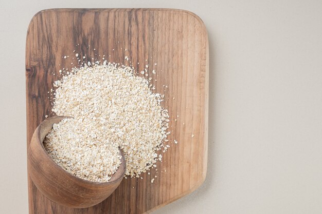 Riz blanc dans une tasse en bois sur un plateau en bois.