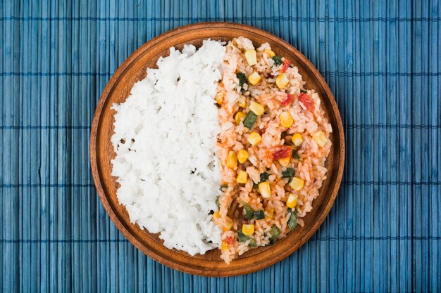 Riz chinois frit et cuit à la vapeur sur une assiette en bois sur le napperon bleu