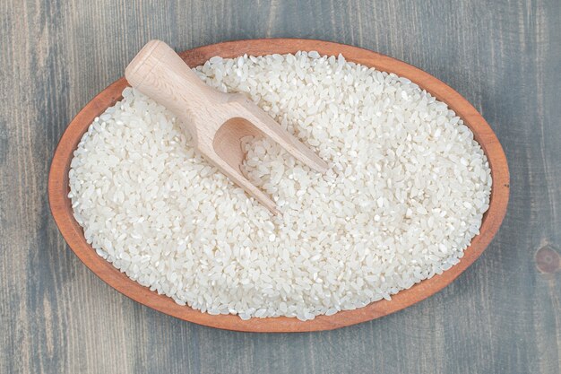 Riz cru sain avec une cuillère en bois sur une table en bois