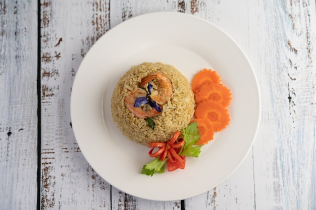 Riz frit aux crevettes sur une plaque blanche composée de tomates et de carottes.