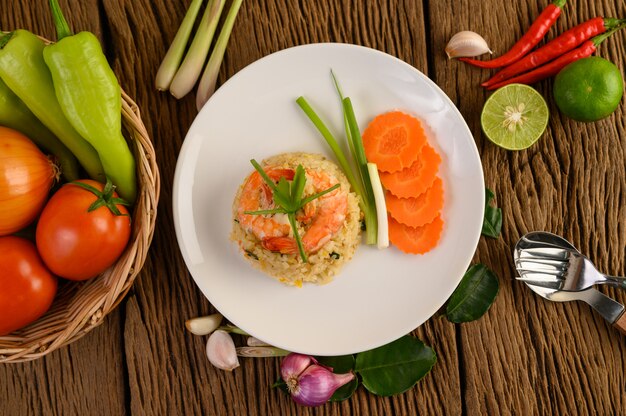 Riz frit aux crevettes sur une plaque blanche sur une table en bois