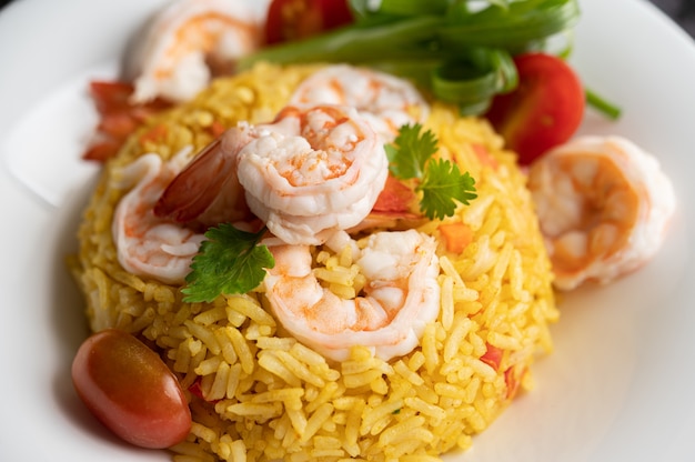 Riz frit aux crevettes avec tomates, carottes et oignons verts dans l'assiette