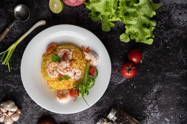 Riz frit aux crevettes avec tomates, carottes et oignons verts dans l'assiette