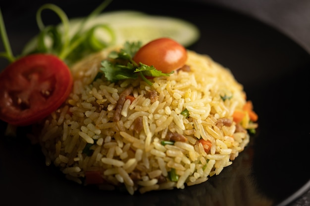 Riz frit avec du porc haché, tomate, carotte et concombre dans l'assiette