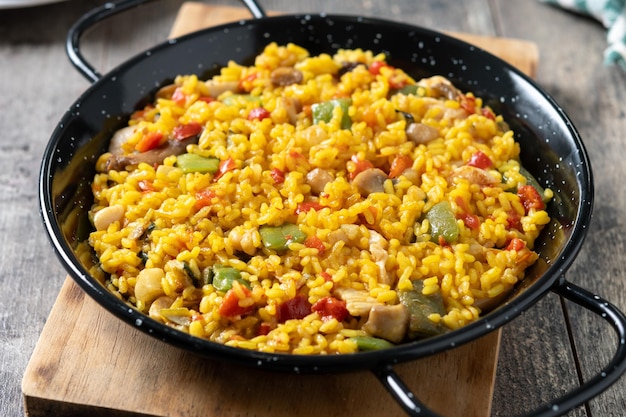 Photo gratuite riz jaune avec du poulet et des légumes sur une table en bois