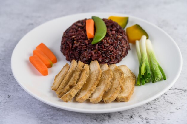 Riz noir sur une assiette avec citrouille, petits pois, carottes, petit maïs et poitrine de poulet cuit à la vapeur.