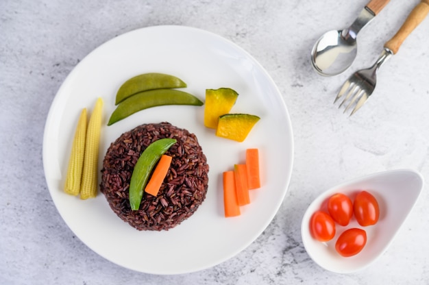 Riz noir sur une assiette avec citrouille, pois, carottes, mini maïs