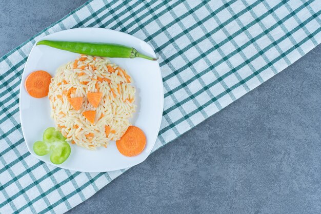 Riz vapeur avec carottes hachées sur plaque blanche.