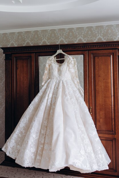 La robe de mariée est suspendue à une armoire
