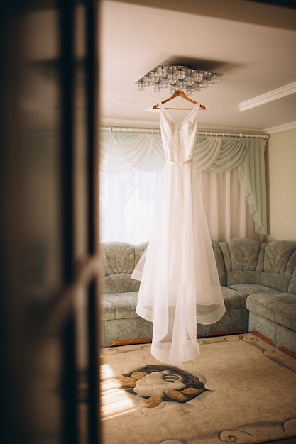 Robe de mariée de la mariée suspendue dans la chambre