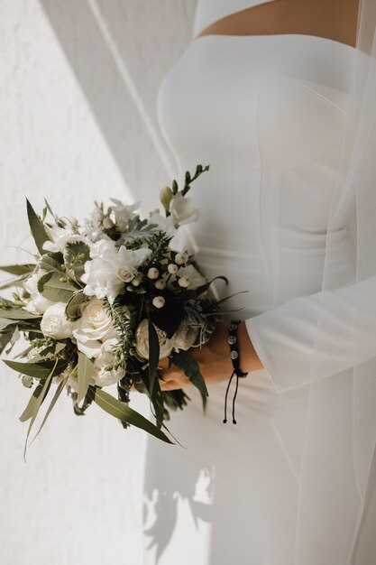 Robe de mariée minimaliste pour la mariée et beau bouquet de mariée fait de fleurs blanches et de verdure, tenue chic