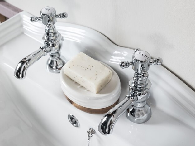 Robinets en acier nouveaux et modernes avec lavabo en céramique dans la salle de bain