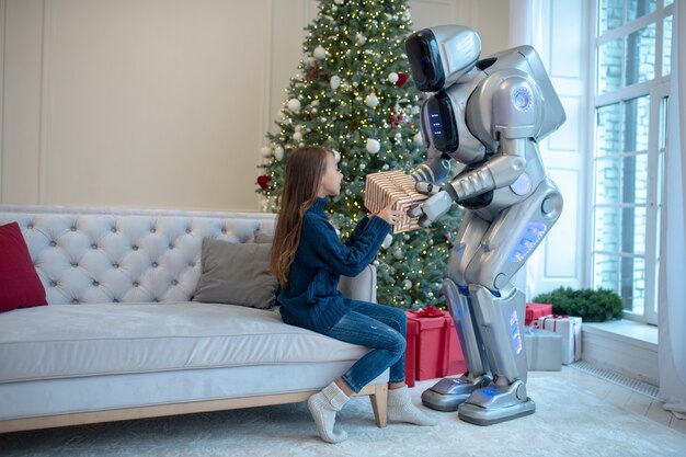 Robot donnant un cadeau de noël à une jeune fille souriante