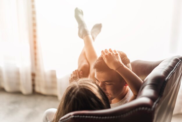 Romantique aimant jeune couple allongé sur un canapé près de la fenêtre