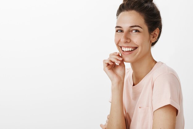 Romantique belle fille posant contre le mur blanc