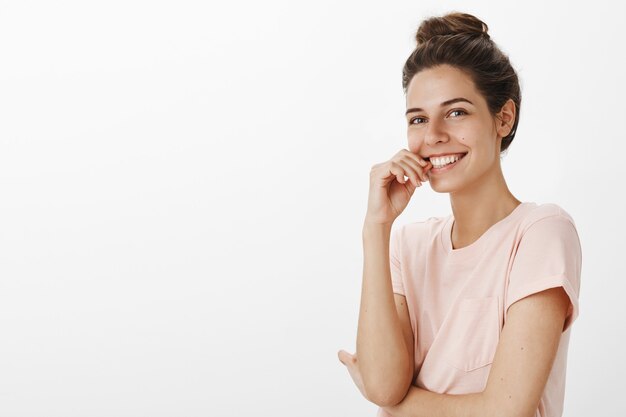 Romantique belle fille posant contre le mur blanc