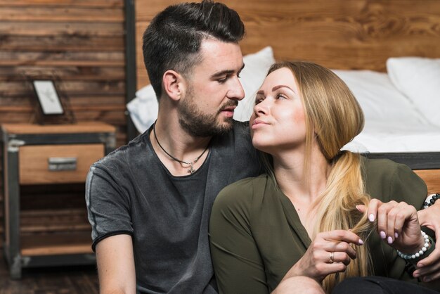 Romantique jeune couple assis dans la chambre à coucher en regardant les uns les autres