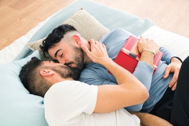 Romantique jeune couple homosexuel allongé sur le lit s&#39;embrasser