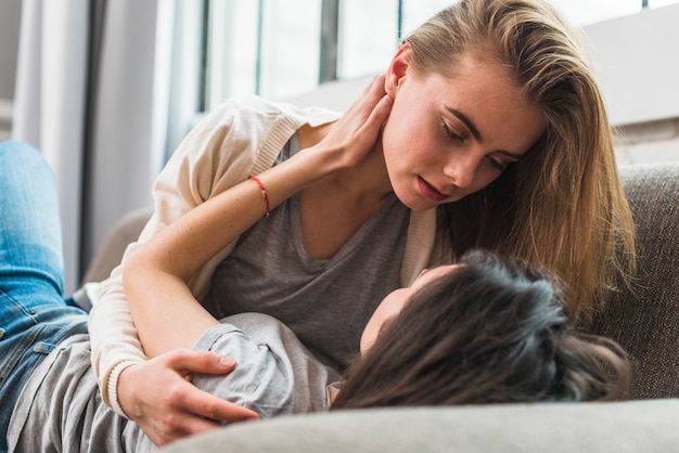 Romantique jeune couple de lesbiennes allongé sur un canapé se regardant